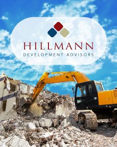 Excavator demolishing a concrete structure under a blue sky with the Hillmann Development Advisors logo prominently displayed, representing the company’s expertise in site redevelopment and construction advisory services.