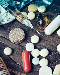 Tabletop full of illicit drugs, pills, and needles