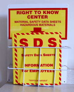 A potential Environmental Health & Safety concern: Wall-mounted "Right to Know Center" station containing bright yellow and red Safety Data Sheets (SDS) labeled for hazardous materials, providing important safety information for employees.